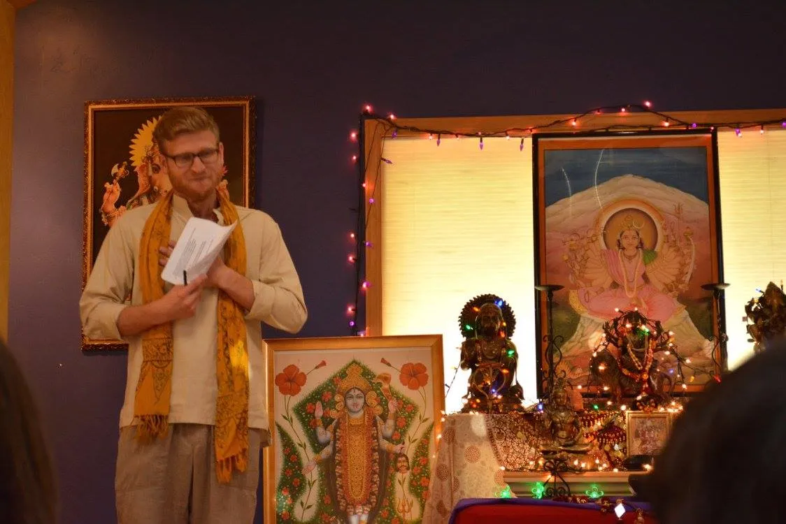 Telfer, moved to tears, speaking at an Alandi Ayurveda Gurukula graduation in front of an altar and paintings of the goddess.