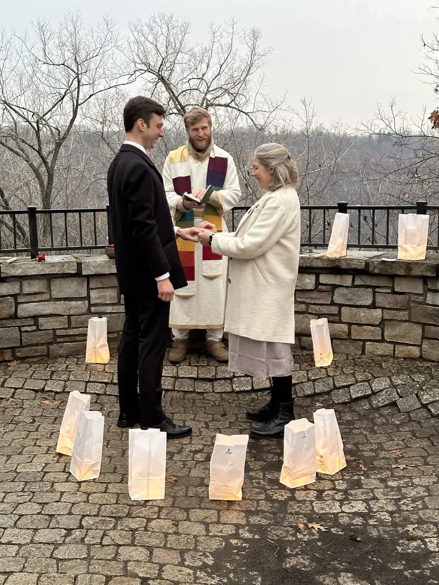 A couple exchanging rings in winter, Telfer officiating, paper lanterns glowing in a circle around them.