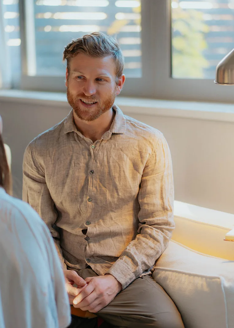 Telfer smiling as he listens to a client in a sunlit session room